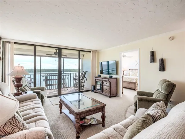 Carpeted living room featuring ornamental molding, ceiling fan, a water view, and expansive sliders