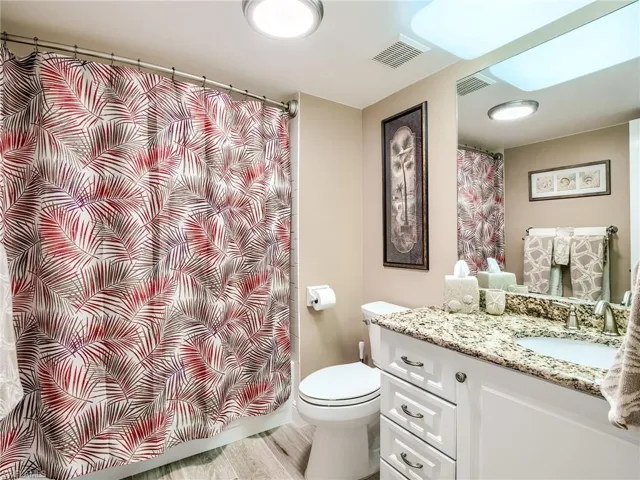 Guest bathroom with porcelain tile floors, oversized vanity, and toilet