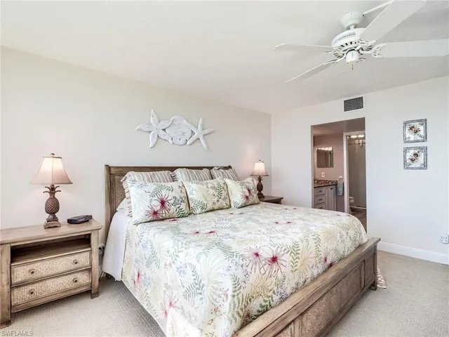 Carpeted master bedroom featuring connected bathroom and ceiling fan
