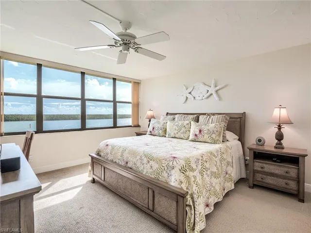 Master bedroom featuring ceiling fan, light carpet, and a water view