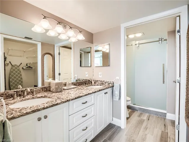 Master bathroom with toilet, porcelain tile flooring, and double sink vanity