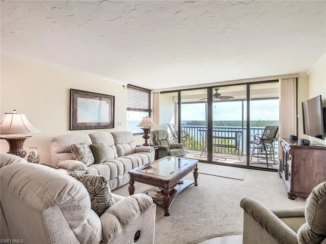 Carpeted living room featuring a water view, expansive new sliders installed in 2018, and crown molding