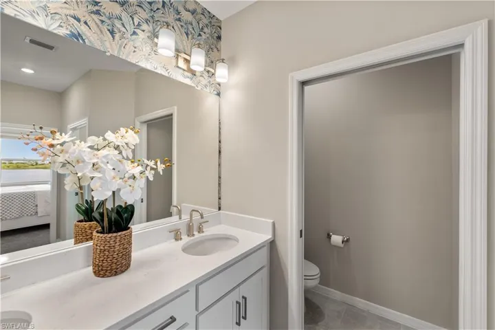 Bathroom featuring dual vanity, tile patterned floors, and toilet