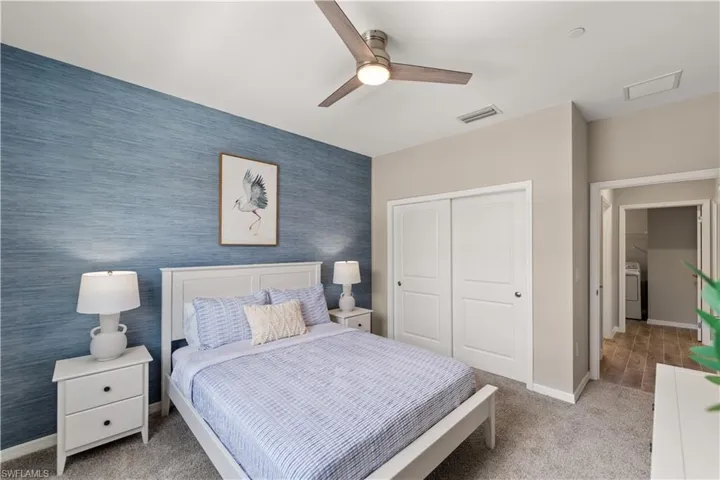 Carpeted bedroom featuring washer / dryer, ceiling fan, and a closet
