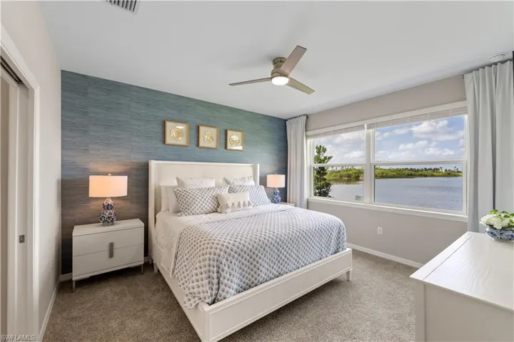 Carpeted bedroom featuring a water view, ceiling fan, and a closet