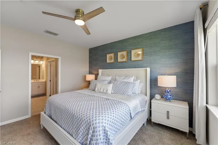 Carpeted bedroom featuring ceiling fan and connected bathroom