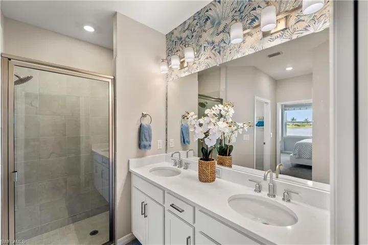 Bathroom featuring a shower with shower door and double sink vanity