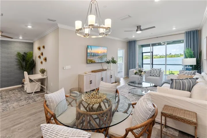 Living room with crown molding, ceiling fan with notable chandelier, and light hardwood / wood-style flooring
