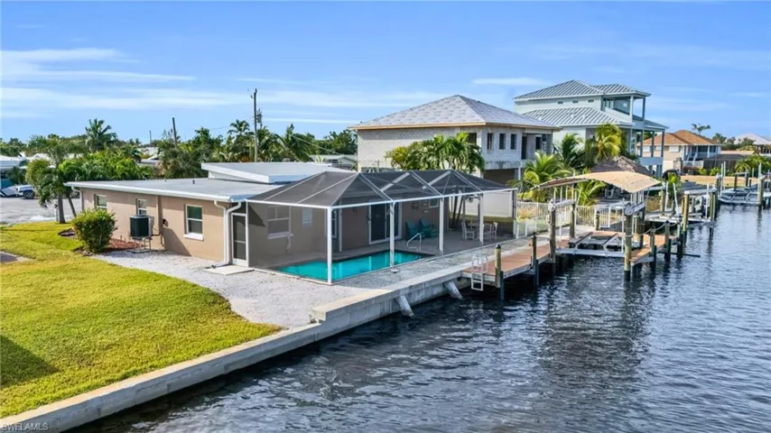 Rear view of property with glass enclosure, a patio, a water view, a lawn, and cooling unit