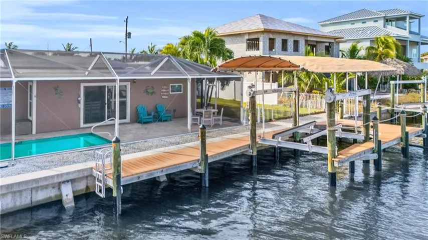 View of dock with a water view, a patio area, and glass enclosure