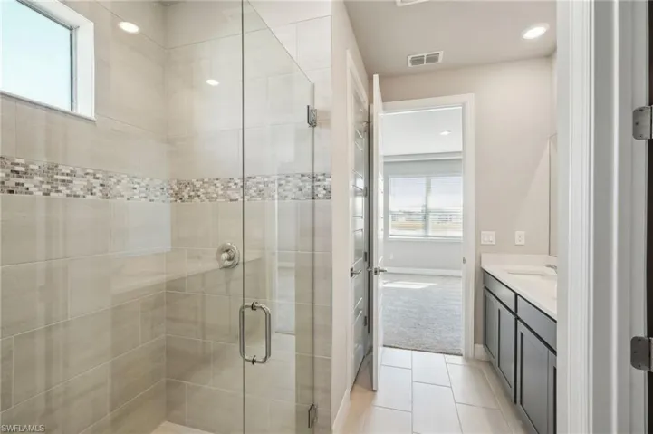 Bathroom featuring tile patterned flooring, vanity, plenty of natural light, and an enclosed shower