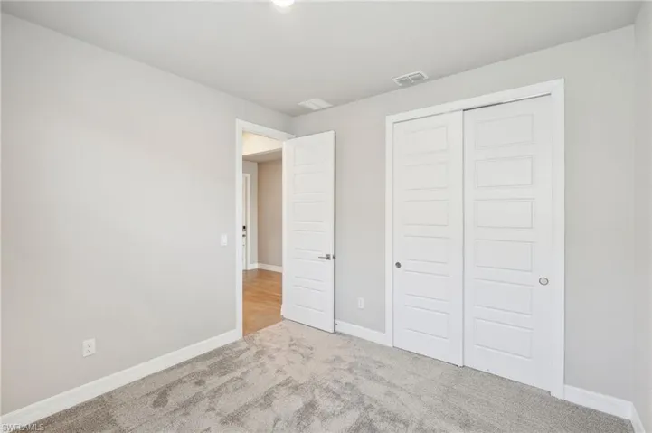 Unfurnished bedroom with light carpet and a closet