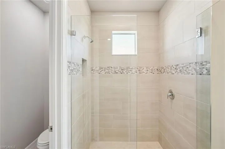 Bathroom featuring tiled shower and toilet