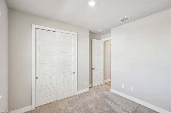 Unfurnished bedroom featuring light colored carpet and a closet