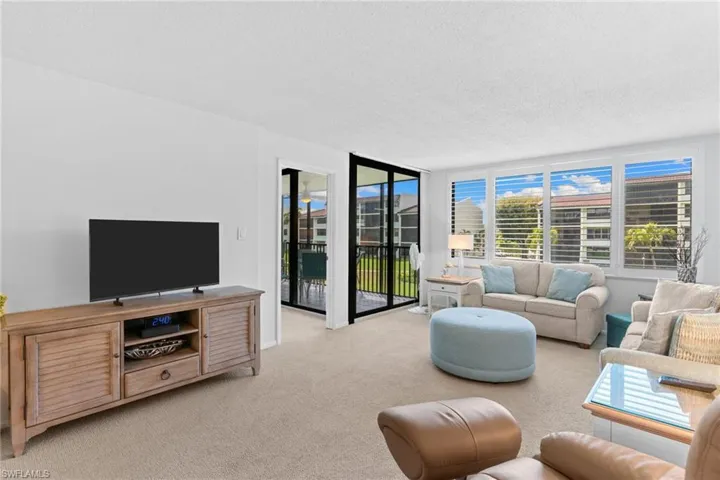 Living room with a textured ceiling, light colored carpet, and expansive windows