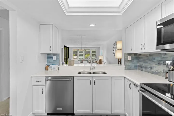 Kitchen with stainless steel appliances, tasteful backsplash, white cabinets, light stone counters, and recessed lighting