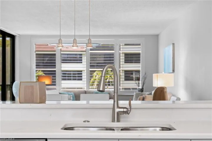 Kitchen with a textured ceiling, plenty of natural light, decorative light fixtures, light stone countertops, and open floor plan