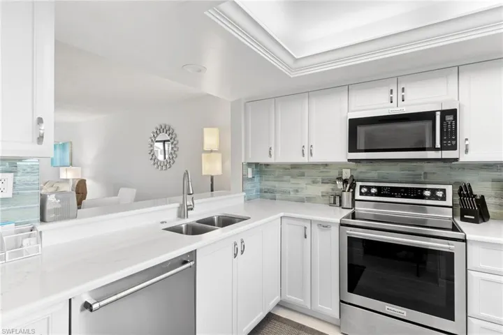 Kitchen with stainless steel appliances, white cabinetry, and tasteful backsplash