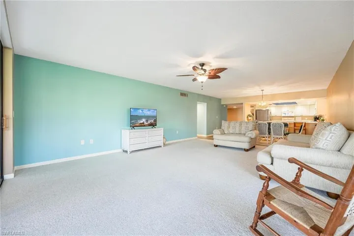 Carpeted living area featuring baseboards and ceiling fan