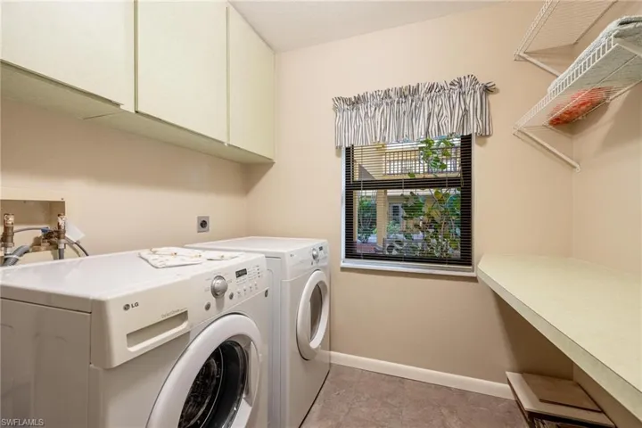 Washroom with cabinet space, washer and dryer, and light tile patterned flooring