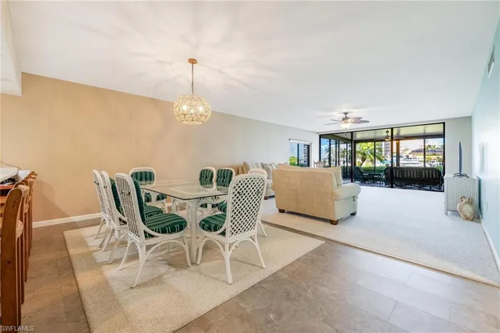 Dining room with ceiling fan, a chandelier, and a wall of windows
