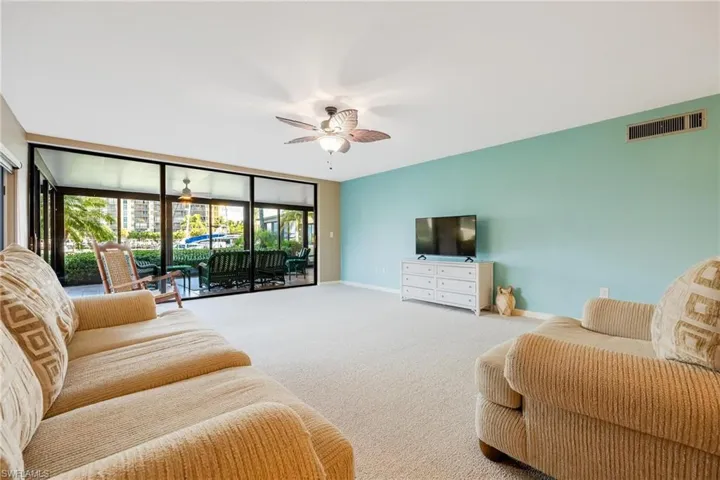Carpeted living room with expansive windows and ceiling fan