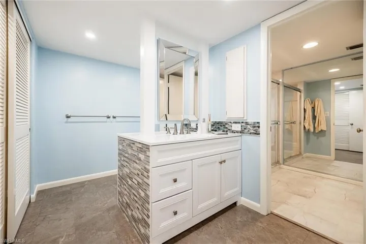 Bathroom featuring vanity, a stall shower, a closet, recessed lighting, and decorative backsplash