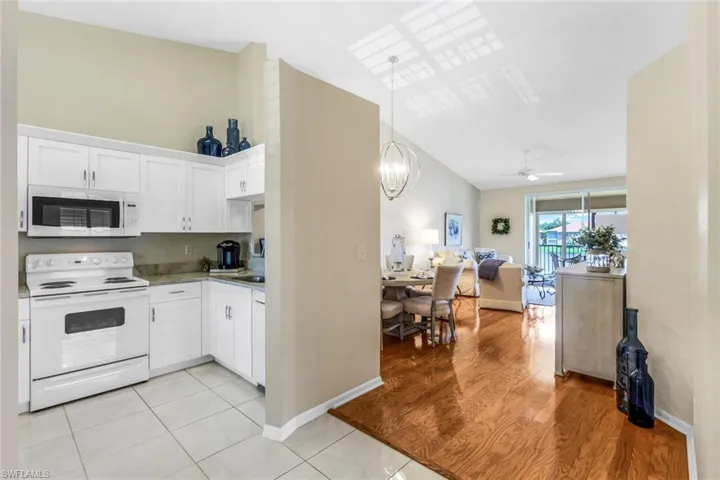 Kitchen featuring white cabinets, ceiling fan with notable chandelier, light hardwood / wood-style flooring, and white appliances