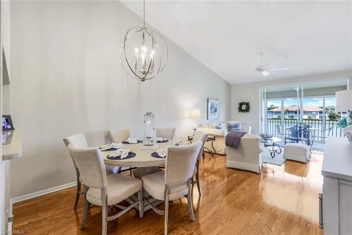 Dining space with light hardwood / wood-style floors, lofted ceiling, and ceiling fan with notable chandelier