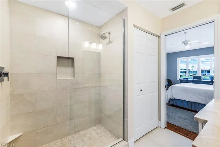 Bathroom with hardwood / wood-style flooring, a shower with shower door, and ceiling fan