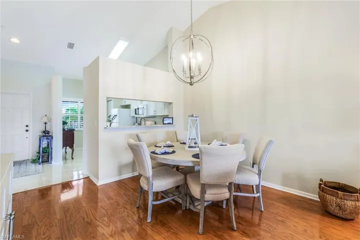Tiled dining space featuring high vaulted ceiling and a notable chandelier