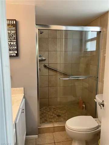 Bathroom with vanity, toilet, a shower with door, and tile patterned flooring