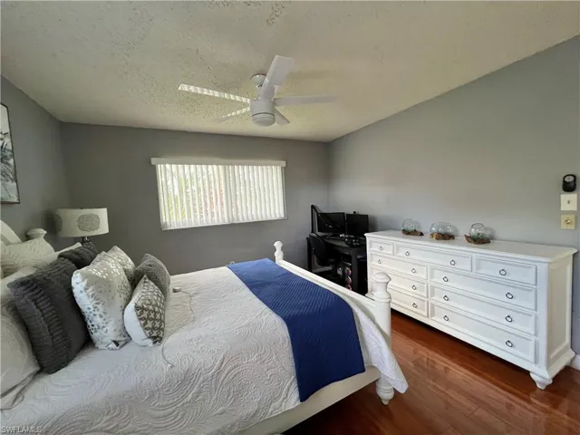 Bedroom featuring a textured ceiling, ceiling fan, and hardwood / wood-style floors