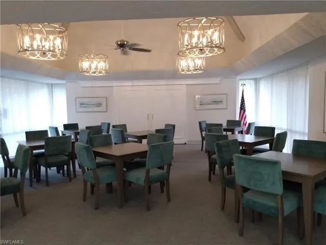 Dining room with ceiling fan with notable chandelier and carpet floors