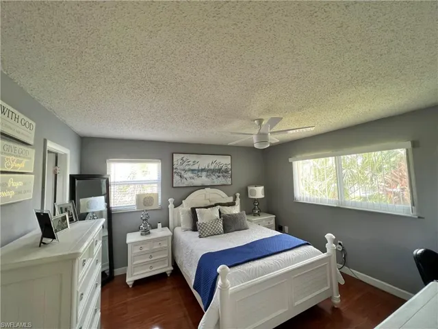 Bedroom featuring dark hardwood / wood-style flooring, a textured ceiling, and ceiling fan