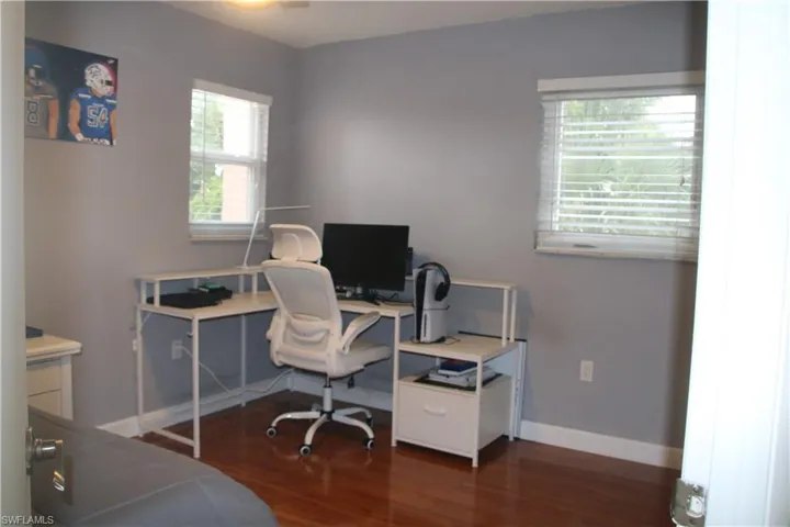 Home office with dark hardwood / wood-style flooring