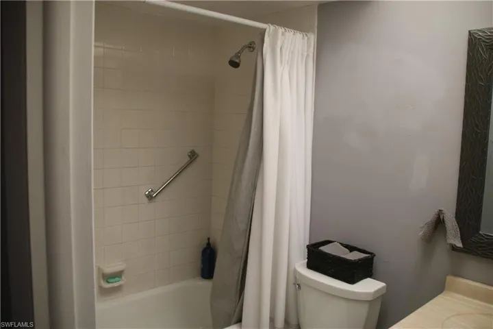Bathroom with toilet and shower / bathtub combination with curtain