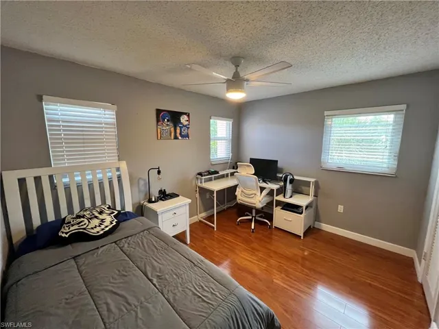 Bedroom featuring ceiling fan, multiple windows, a textured ceiling, and hardwood / wood-style flooring