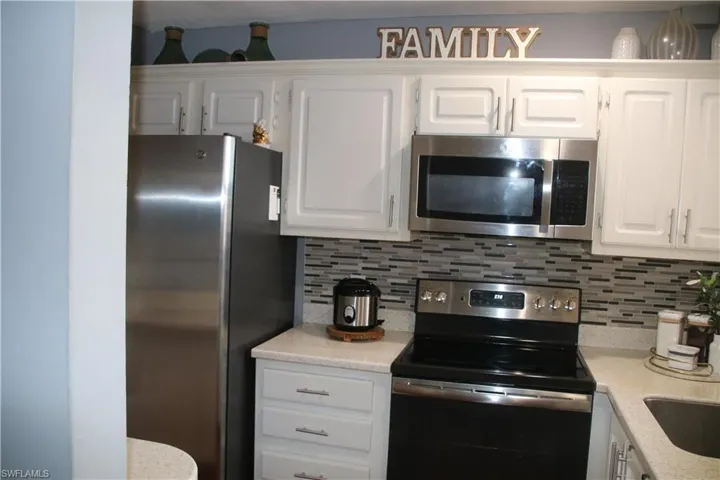 Kitchen with decorative backsplash, stainless steel appliances, and white cabinets