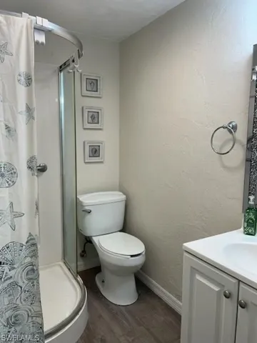Bathroom with a shower, vanity, toilet, and wood-type flooring