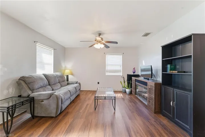 Living area with dark wood-style flooring and ceiling fan