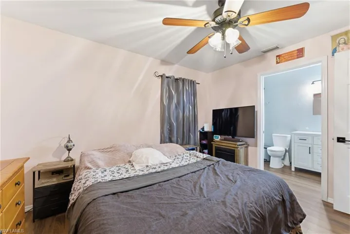 Bedroom featuring wood finished floors, ceiling fan, and ensuite bath