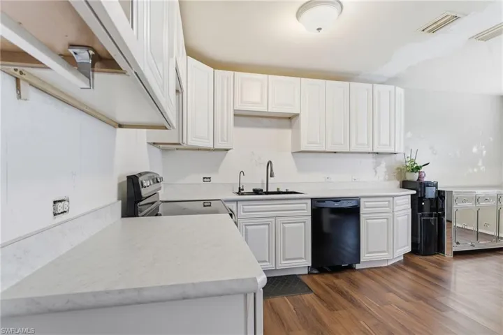 Kitchen featuring light countertops, dark wood-style floors, electric stove, and dishwasher