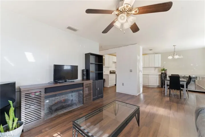 Living room featuring dark wood finished floors, a fireplace, a ceiling fan, and a chandelier
