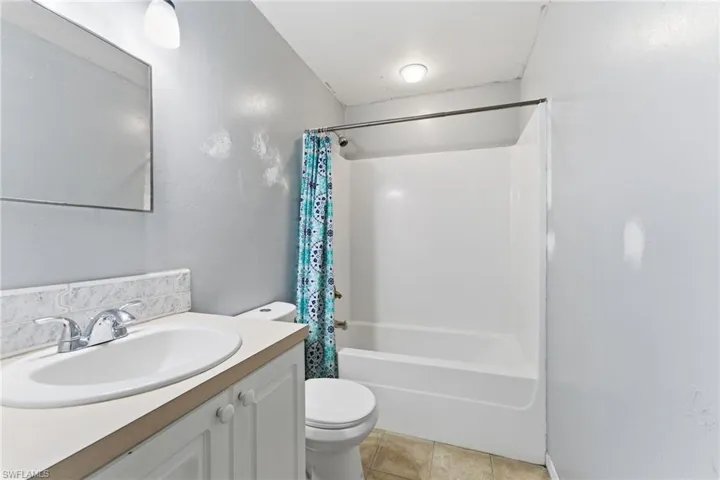 Bathroom featuring vanity, shower / bath combination with curtain, and light tile patterned floors