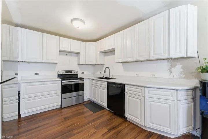 Kitchen with dark wood finished floors, appliances with stainless steel finishes, white cabinetry, and light countertops