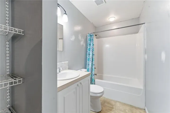 Bathroom with vanity, shower / bath combo, and light tile patterned floors