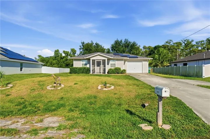 Single story home with roof mounted solar panels, concrete driveway, and an attached garage