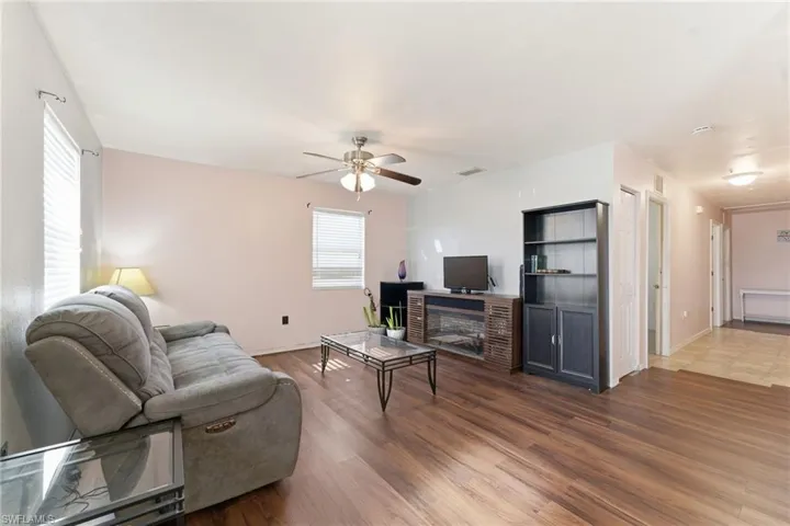 Living room with a fireplace, wood finished floors, and ceiling fan