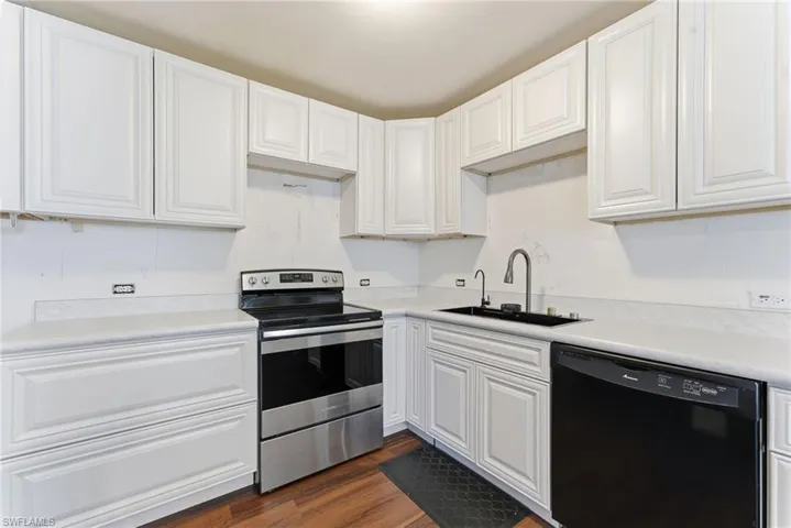 Kitchen with stainless steel electric stove, white cabinets, dishwasher, and light countertops